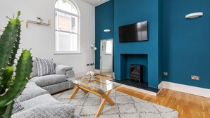 A modern living room with a glass coffee table, grey sofa, and a fireplace. - Unique Property in the Heart of Winchester (Winchester)