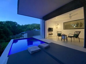 Ein moderner Poolbereich im Freien mit Blick auf die Landschaft, einem Deckenventilator und Sitzmöbeln.