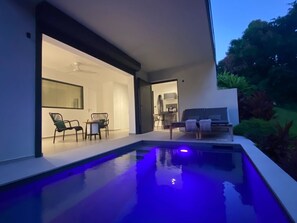 Ein moderner Poolbereich im Freien mit freiem Blick auf den angrenzenden Wohnbereich, inklusive Essbereich und Sitzgelegenheiten.
