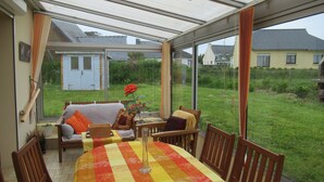 A conservatory with a dining table, chairs, and a sofa. - DETACHED HOUSE 100 M2 ON A 936 M2 ENCLOSED PLOT AT THE END OF A CUL-DE-SAC (Porspoder)