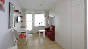 A modern living room with a white sofa, a red sofa, a dining table with chairs, and a large mirror on the wall. - House Metropol 254, OB (Westerland)