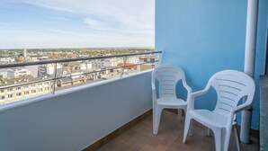 A balcony with two white plastic chairs, a blue wall, and a view of a cityscape. - House Metropol 254, OB (Westerland)