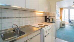 A compact kitchen with a sink, stove, and coffee maker.