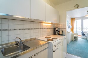 A compact kitchen with a sink, stove, and coffee maker.