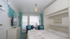 A hotel room with a bed, a desk, a chair, a television, and a window with curtains.