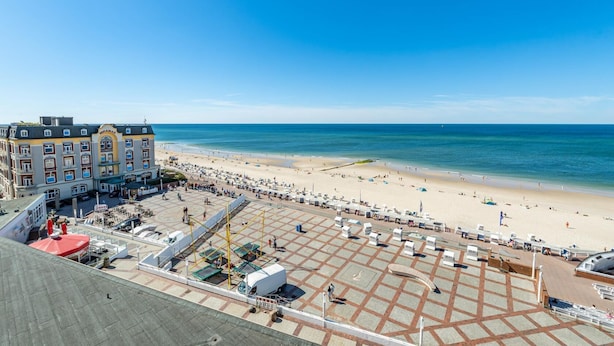 A hotel with a beach view, outdoor seating, and a parking area.