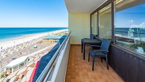 A balcony with a view of a beach and a pool area.
