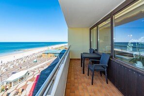 Een balkon met uitzicht op een strand en een zwembad.
