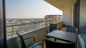 A balcony with a table and chairs, offering a view of a cityscape. - Haus Metropol 175 OB (Westerland)