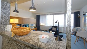 A modern hotel room with a granite countertop, a wicker basket, a white ashtray, and a black floor lamp. - Haus Metropol 175 OB (Westerland)
