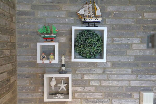 A brick wall with various decorative items including a ship, a framed plant, and small figurines.