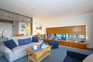 A living room with a sofa, a coffee table, a television, and a bookshelf.