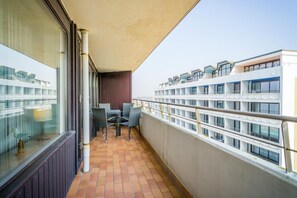 A balcony with a table and chairs, a tiled floor, and a view of adjacent buildings.