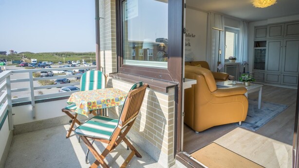 A balcony with a table and chairs, a sofa, and a view of a parking lot. - Haus Birgit 6-15 Steinmannstraße 15. In Zentraler und Strandnaher Lage in Westerland, Liegt Diese Gemütliche, Liebevoll Eingerichtete Ferienwohnung. Nur 100m von der Promenade/strand Sowie den Kureinrichtungen und Schwimmbad en (Westerland)