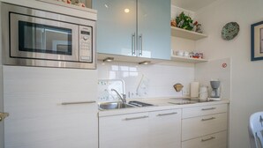 A modern kitchen with a built-in oven, a sink, and a coffee maker. - Haus Birgit 6-15 Steinmannstraße 15. In Zentraler und Strandnaher Lage in Westerland, Liegt Diese Gemütliche, Liebevoll Eingerichtete Ferienwohnung. Nur 100m von der Promenade/strand Sowie den Kureinrichtungen und Schwimmbad en (Westerland)
