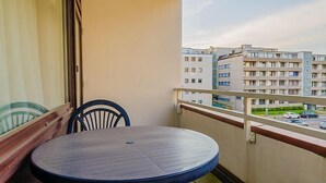 Un balcón con una mesa redonda y dos sillas, con vista a una zona residencial con edificios de varios pisos.