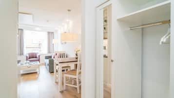 A modern hotel room with a dining area, a sofa, a chair, and a wardrobe.