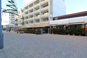 A multi-story hotel with a modern architectural design, featuring balconies and a ground-level restaurant.
