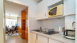 Eine moderne Küche mit weißen Schränken, einer integrierten Mikrowelle, einer Kaffeemaschine und einem Spülbecken.