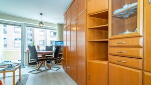 Eine moderne Küche mit Holzausstattung, ein Essbereich mit Tisch und Stühlen und ein Ausblick ins Freie durch große Fenster.