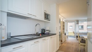 Una cucina moderna con mobili bianchi, un piano di lavoro nero e un forno a microonde integrato.