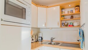 A compact kitchen with a microwave, coffee maker, sink, and storage cabinets. - Windhuk 1-11 am Strand (Westerland)