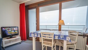 Un balcon équipé d’une table à manger, de chaises, d’un téléviseur et d’une lampe.