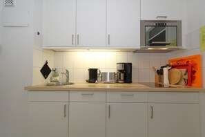 A kitchen with white cabinets, a stainless steel coffee maker, a microwave, and a sink. - House Sylter Welle 5-39 WB (Sylt/Westerland)