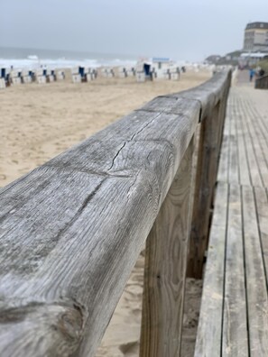 Een houten looppad dat naar een strand leidt, met een zandstrand en de oceaan op de achtergrond.