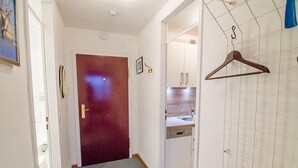 A hallway with a wooden door, a hanging coat rack, and a bathroom with a sink and cabinets. - House Sylter Welle 8-87, OB (Sylt/Westerland)