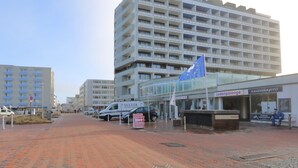 Un hotel de varios pisos con balcones, un restaurante y una tienda de banderas.