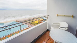 En balkong med utsikt över stranden och poolområdet.