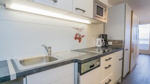 Ett modernt kök med en diskho i rostfritt stål, en mikrovågsugn och en kaffebryggare.