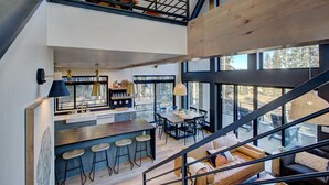 Una cocina moderna con barra, ventanas amplias y una escalera que conduce a un nivel superior.