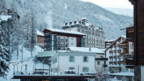 Een bergstad bedekt met sneeuw, met een meer verdiepingen tellend hotel met balkons en een skilift op de achtergrond.