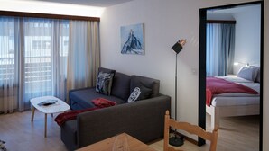 Een moderne woonkamer met een bank, een eettafel en een bed.