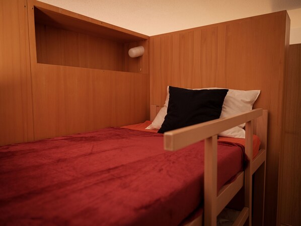 A small, single-bed room with wooden walls and a red bedspread. - Silence by Interhome (Zermatt)