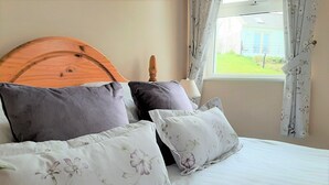 Een keurig opgemaakt bed met bloemenkussens en een houten hoofdbord.