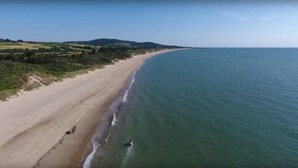 Een kuststrand met een zandstrand en helder uitzicht op zee.