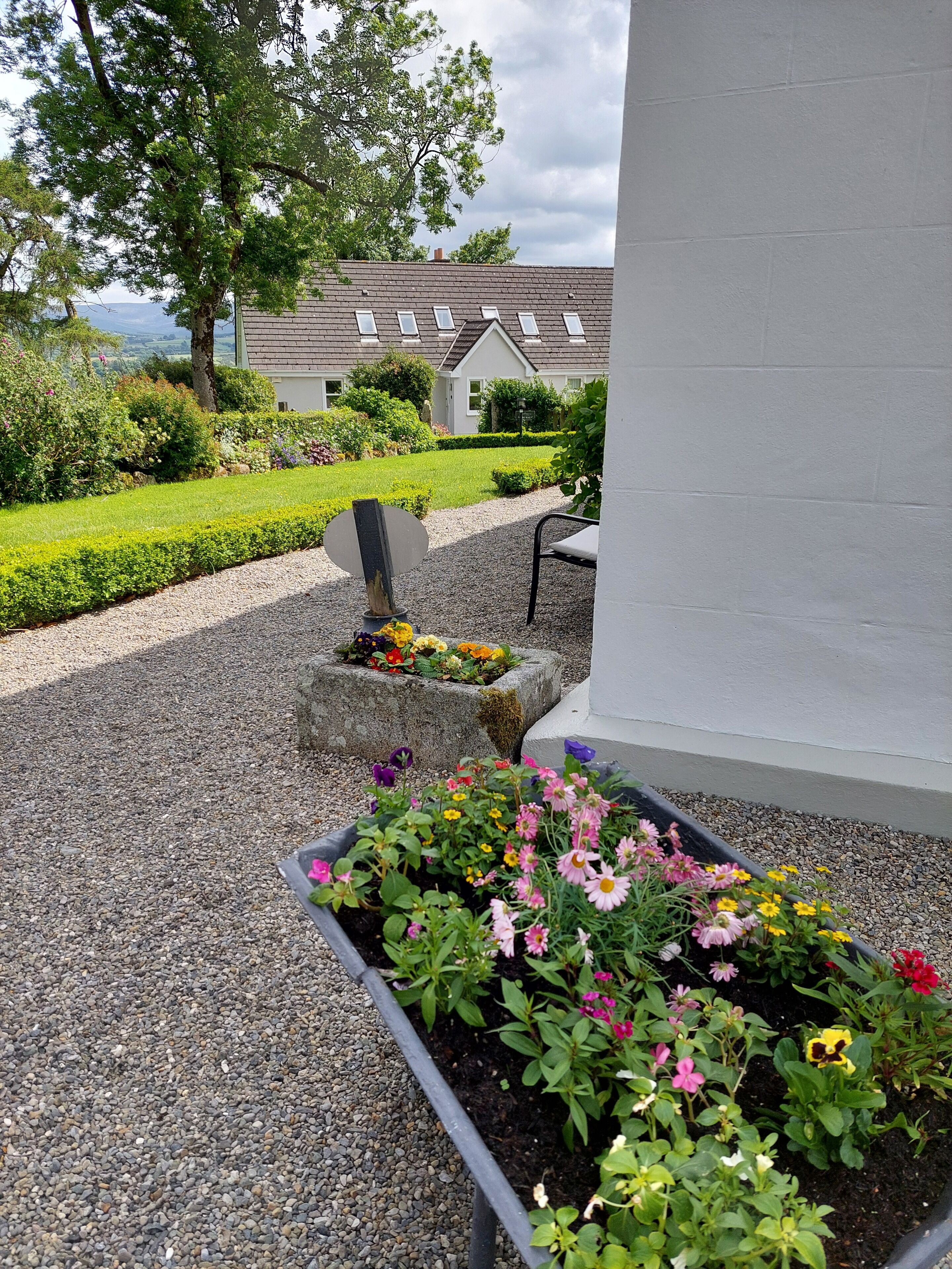 A garden with flower beds, a gravel path, and a building in the background.