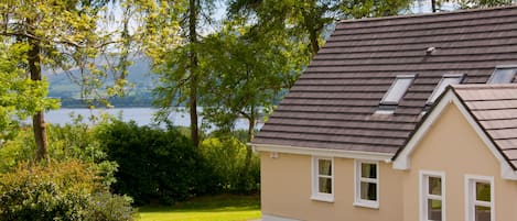 A house with a sloped roof, a driveway, and a view of a lake.