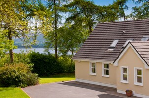 Una casa con techo inclinado, entrada para coches y vista al lago.