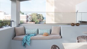 A balcony with a cushioned seating area, a woven basket, and a view of the cityscape. - Antigoni's Seaside Lodge (Rethymno)