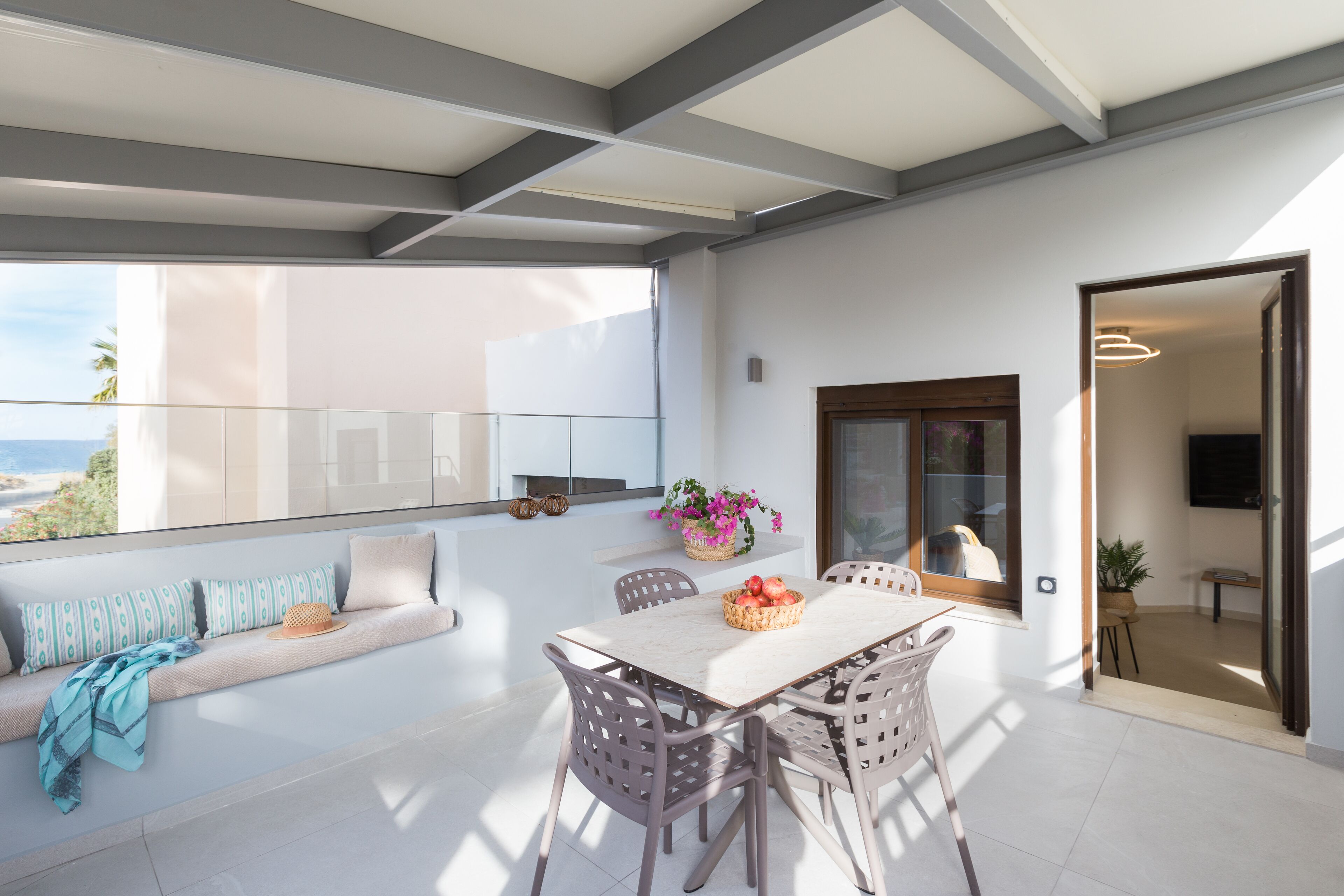 A modern living room with a balcony, a dining area, and a view of the sea.