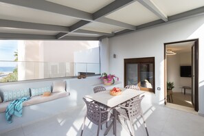 A modern living room with a balcony, a dining area, and a view of the sea. - Antigoni's Seaside Lodge (Rethymno)