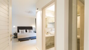 A modern bedroom with a large bed, a bedside table, and a nightstand. - Antigoni's Seaside Lodge (Rethymno)