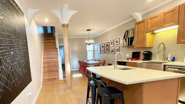 A modern kitchen with a central island, wooden flooring, and a staircase leading to a dining area. - Larry's Lancaster Landing: 3 bedroom row house, walkable to downtown Lancaster (Lancaster)