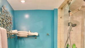 A bathroom with a blue wall, a glass shower enclosure, a wooden bathtub, and a towel rack with folded towels. - Larry's Lancaster Landing: 3 bedroom row house, walkable to downtown Lancaster (Lancaster)