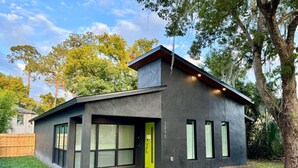 A modern house with a flat roof, large windows, and a bright yellow door. - The Butterfly House: with sauna and fully-fenced yard  (Sanford)