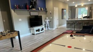 A living room with a foosball table, a television, and a Star Wars figure. - The Billiard: super fun home close to downtown with fully-fenced yard (Sanford)